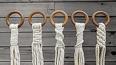 five different ropes with wooden rings hanging from them on a wood wall, one is white and the other is brown