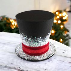 a black top hat with red and silver glitters on it sitting on a table