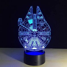 a blue light up star wars millennium falcon model on a black stand with the lights turned on