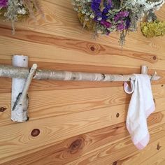 a wooden wall with flowers hanging from it's hooks and two towel racks on the wall