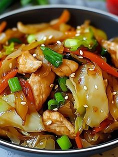 chicken and vegetable stir fry in a bowl with sesame seeds, carrots, celery, and green onions