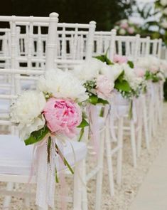 rows of white chairs with pink and white flowers tied to the back, along side each other