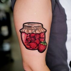 a woman's arm with a jar of strawberries tattoo on it