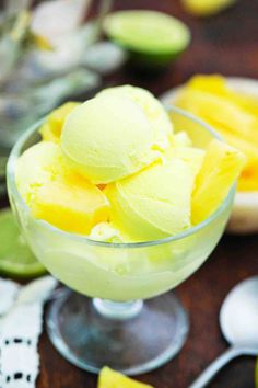 a glass bowl filled with ice cream next to sliced limes