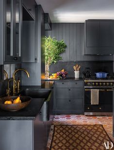 a kitchen with black cabinets and an orange rug on the floor in front of it