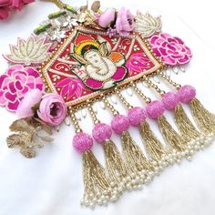 an embroidered piece with tassels, beads and flowers on a white cloth background