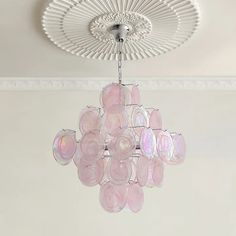 a pink chandelier hanging from the ceiling in a room with white walls and ceilings