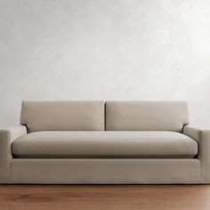 a couch sitting on top of a hard wood floor next to a white painted wall