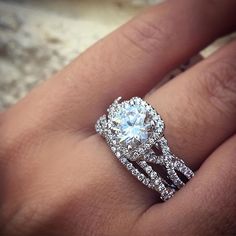 a woman's hand with a diamond ring on top of her wedding band and an engagement ring in the middle