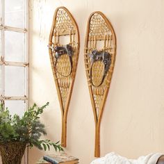 two wooden sleds are hanging on the wall next to a plant in a vase