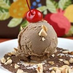 an ice cream sundae on a white plate topped with chocolate chips and a cherry