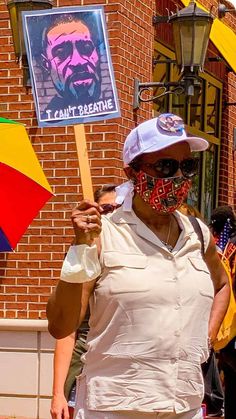 a woman wearing a face mask and holding an umbrella in front of a brick building