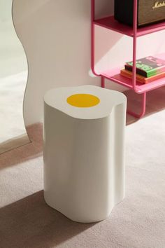 a white stool sitting on top of a carpeted floor next to a book shelf