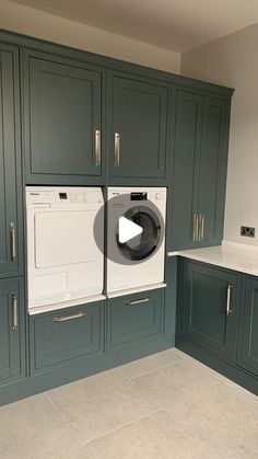 a washer and dryer in a kitchen with dark green cabinetry on the walls