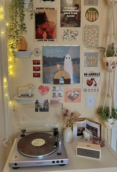 a record player sitting on top of a table next to a wall covered in pictures