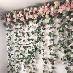 the wall is covered with pink flowers and greenery