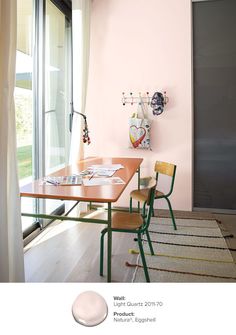 a dining room with pink walls and green chairs in front of a table that is next to a sliding glass door