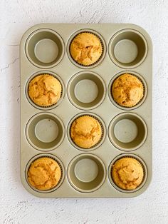 muffins in a pan on a white wall with the top half missing from it