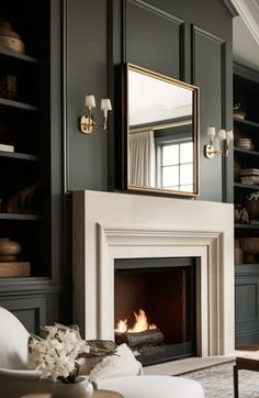 a living room filled with furniture and a fire place under a mirror on the wall