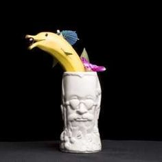 a white vase with a banana in it and a face on the inside of it