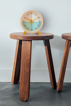 two wooden stools with an alarm clock on each side and one sitting on the floor