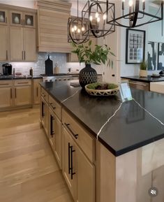 a large kitchen with an island in the middle and lights hanging from it's ceiling