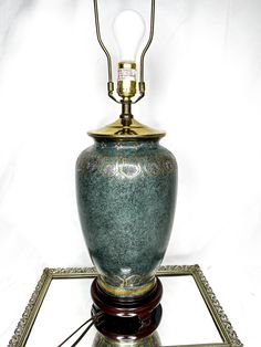 a green vase sitting on top of a metal stand with a light bulb in it