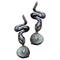 Behold the exquisite "Serpent and Labradorite Earrings" by Rossella Ugolini, an unparalleled expression of Italian artistry and bohemian allure. Handcrafted in burnished sterling silver, these unique earrings bring together the mystical charm of snakes, the ethereal beauty of labradorite, and the timeless sparkle of white diamonds. The centerpiece of these striking earrings is a pair of bold, burnished sterling silver snakes. The burnished finish not only lends them a rustic charm but also besto Elegant Handmade Snake Earrings, Handmade Elegant Snake Earrings, Wax Carving, Labradorite Earrings, Ethereal Beauty, White Diamonds, Unique Earrings, Rustic Charm, Diamond White