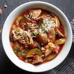 a bowl of soup with meat, vegetables and parmesan cheese