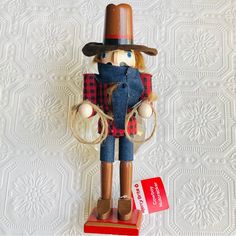 a wooden nutcracker with a hat and scarf on it's head holding a red tag