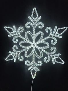 a lighted snowflake ornament on a black background