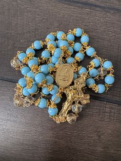 Divine Elegance Awaits: A Handcrafted Gold Rosary with Serene Baby Blue Beads Immerse yourself in a prayer experience wrapped in grace and beauty with our exquisite handmade gold rosary. This piece is a labor of love, meticulously crafted to bring a touch of divine opulence to your spiritual moments: Luminous 8mm Baby Blue Round Beads: Each bead in this heavenly rosary is a serene baby blue, softly encapsulated in gold, radiating a captivating glow. The gentle hue invokes a sense of peace, elevating your prayer time with its tranquil beauty. Exquisite Czech Glass 'Our Father' Bead: Elevating its uniqueness, the 'Our Father' bead is adorned with a Czech glass chandelier design, topped with gold. This accent bead not only enhances the rosary's elegance but also serves as a focal point for me Spiritual Light Blue Jewelry With 8mm Beads, Blue Beaded Rosary As A Gift, Spiritual Beaded Rosary For Blessing, Gold Rosary With 8mm Beads For Meditation, Adjustable Blue Beaded Rosary, Gold Rosary For Meditation, Blue 108 Beads Spiritual Rosary, Spiritual Blue Rosary With 108 Beads, Spiritual Blue Rosary With Round Beads