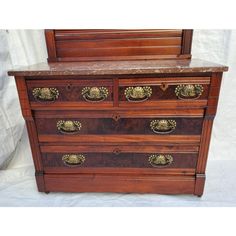 an old wooden dresser with marble top and brass pulls on the drawers, against a white background