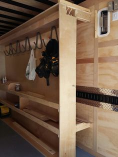 the inside of a storage room with wooden shelves and bags hanging from hooks on the wall