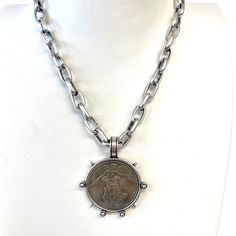 a necklace with a coin on it and a chain attached to the back of it