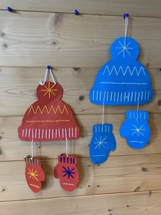 three handmade christmas decorations hanging on a wooden wall with blue and red mittens