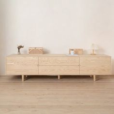 a wooden dresser sitting on top of a hard wood floor next to a white wall