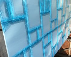 blue glass blocks are stacked on top of each other in the process of being painted