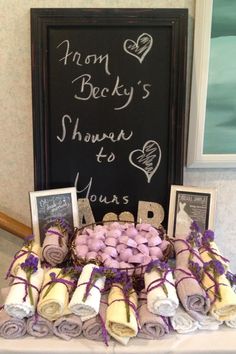 a table topped with lots of rolled up blankets next to a chalk board and framed pictures