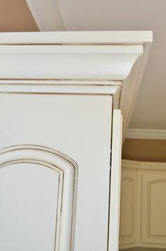 an old white cabinet with a wooden door in the middle and a brown handle on top