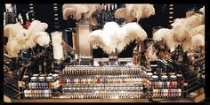 an assortment of cosmetics and other items on display in a store with feathers hanging from the ceiling