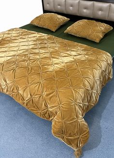 a bed with gold comforter and pillows on it in a blue carpeted room