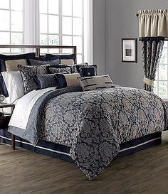 a bed with blue and white comforters in a bedroom next to a window on a hard wood floor