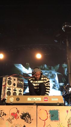 a man standing on top of a stage next to an electronic equipment set up in front of him