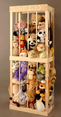 a wooden shelf filled with lots of stuffed animals on top of a floor next to a wall