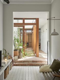 an open living room and dining area with wooden doors leading to the outside patio, along with potted plants