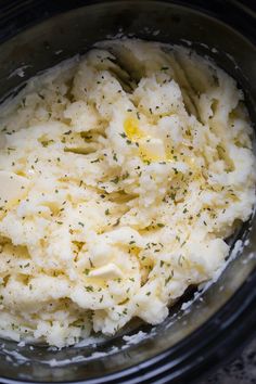 mashed potatoes in a crock pot with butter and seasoning sprinkled on top