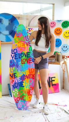 a woman standing next to a surfboard made out of letters