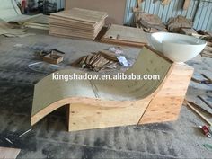 an unfinished skateboard ramp is being built in a garage with lots of wood pieces around it