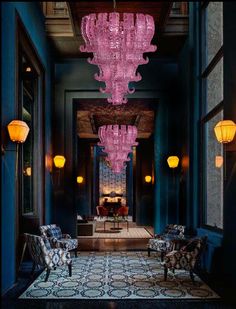 a large chandelier hanging from the ceiling in a room with chairs and lamps